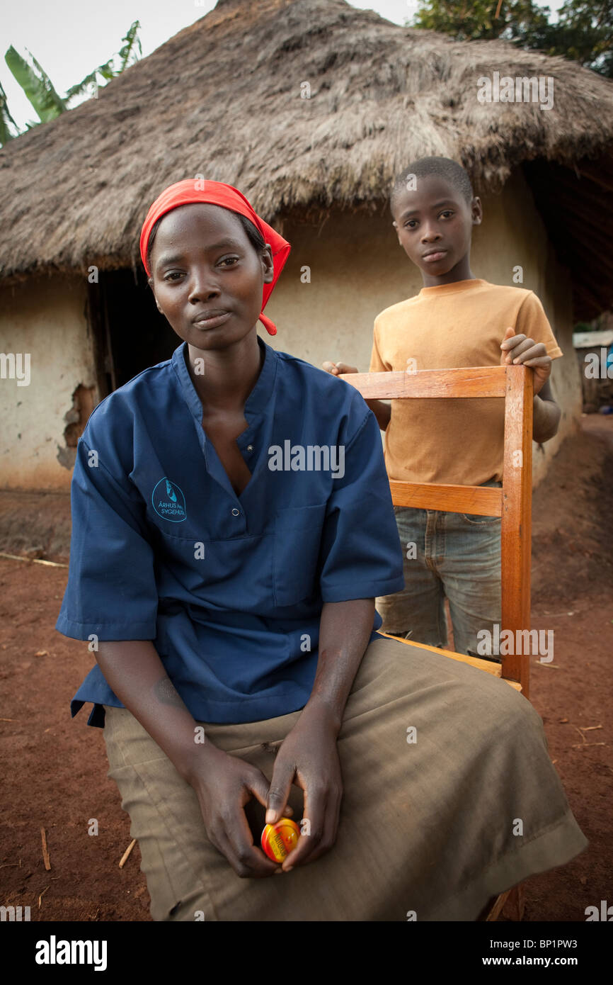 Una joven y su hermano sentarse fuera de su casa de pasto en Kakamega, Kenia. Foto de stock