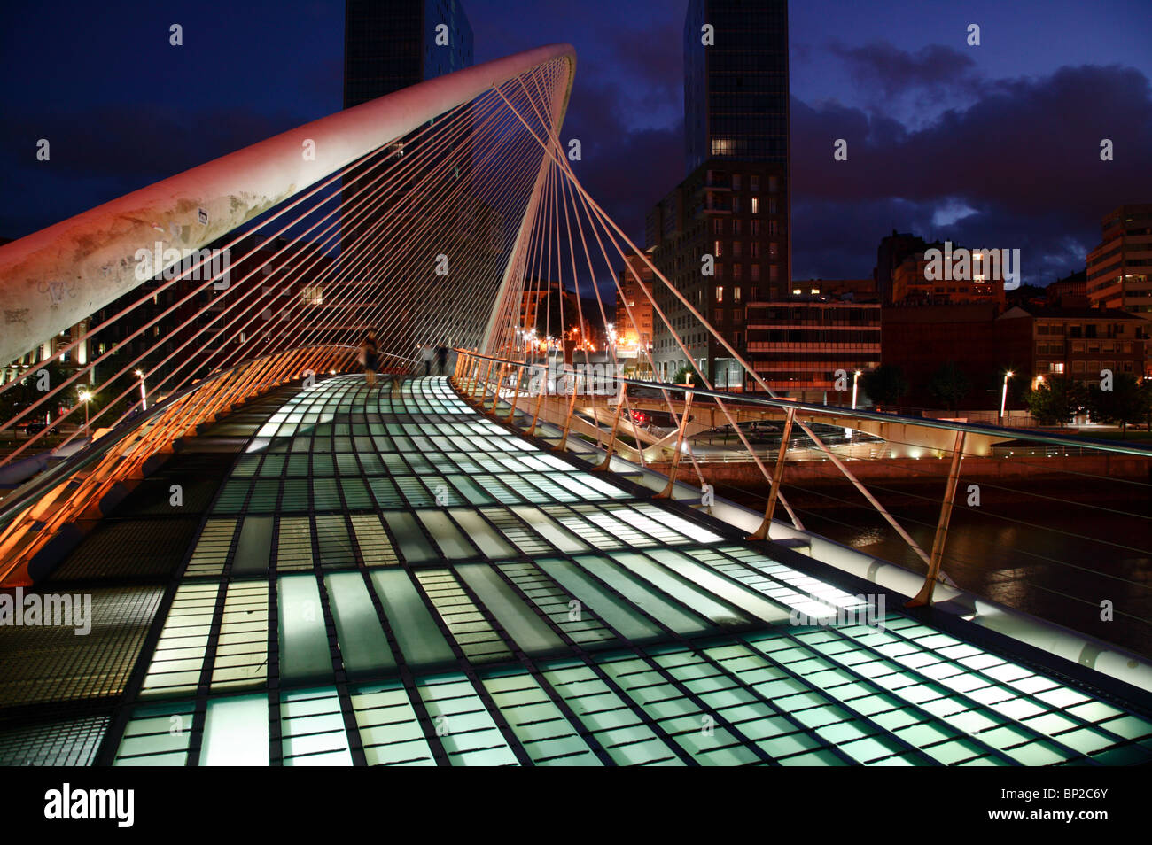 Imagen nocturna del Puente Zubizuri cruzando el río Nervión en Bilbao, España. Foto de stock