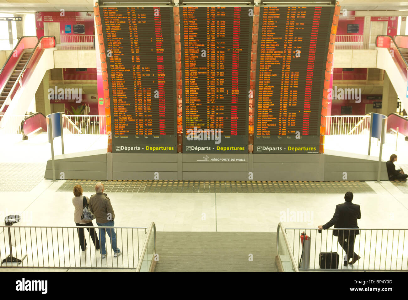Los pasajeros mire la placa de salidas en el aeropuerto Charles de Gaulle en París, lleno de vuelos cancelados o aplazados Foto de stock