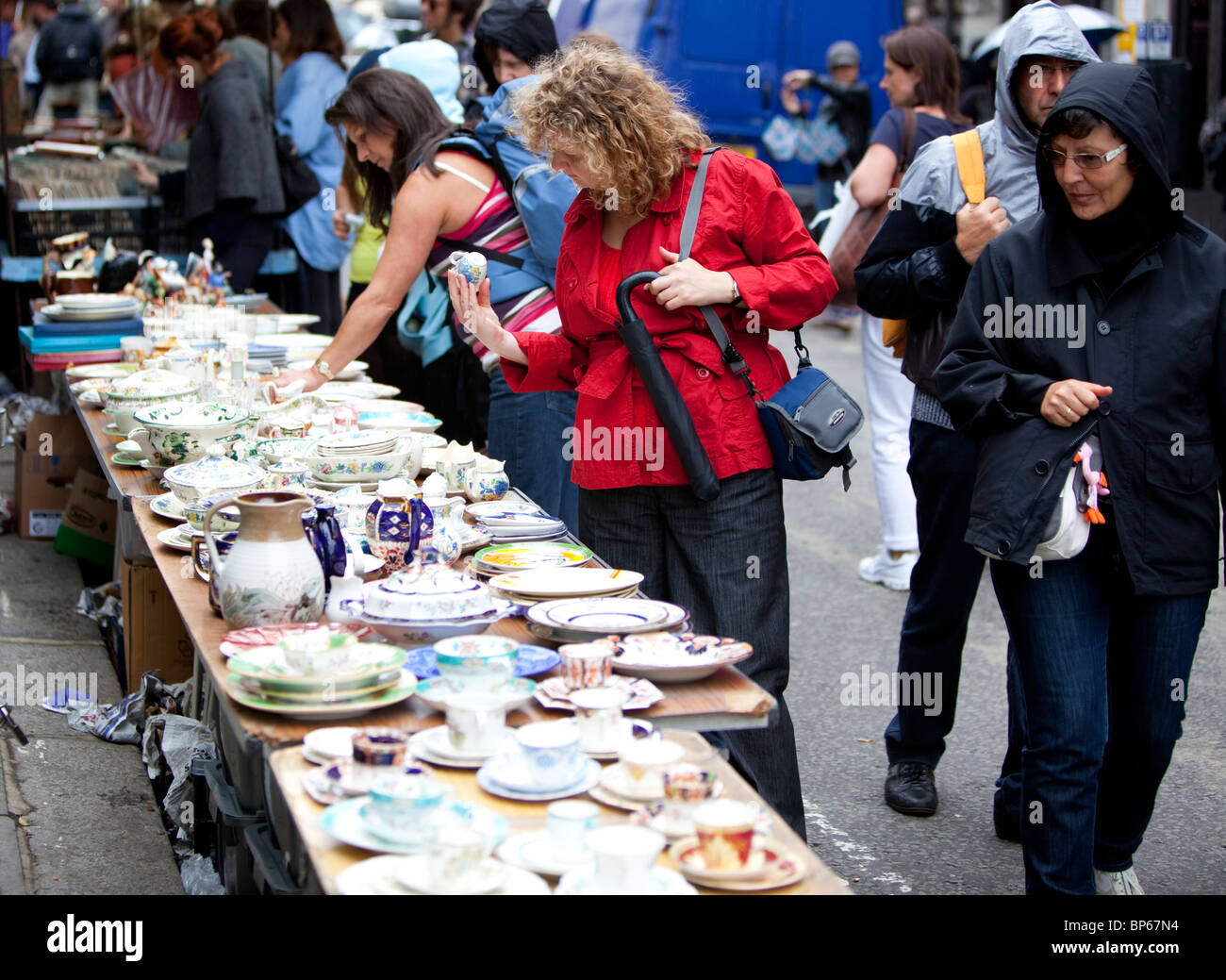 Las personas en el mercado de Notting Hill revisando viejos vajilla, Londres, Inglaterra, Reino Unido. Foto de stock