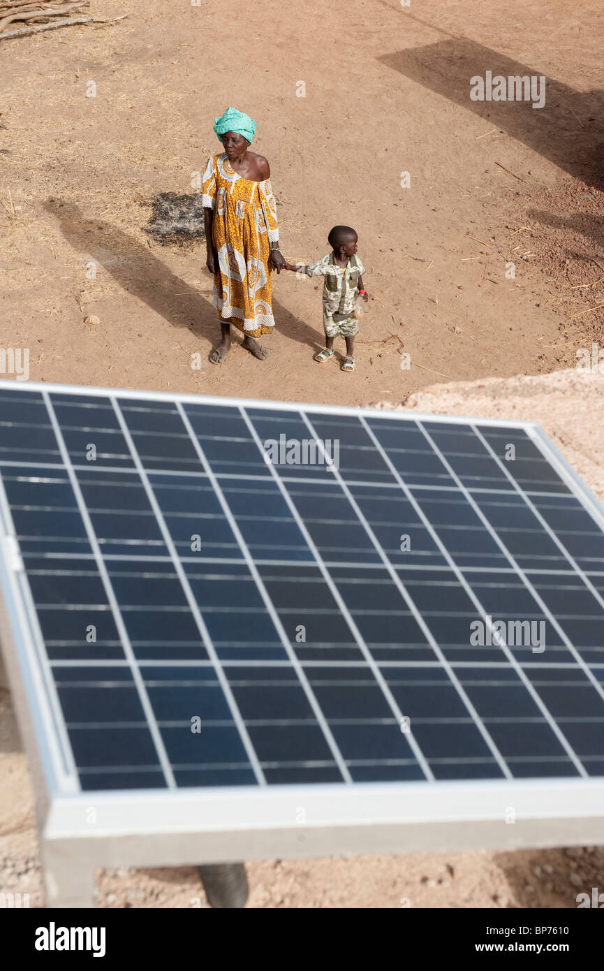 África occidental, Malí , panel solar en el tejado de la estación de recarga de batería solar en aldea Dialkoro , mujer con niño Foto de stock