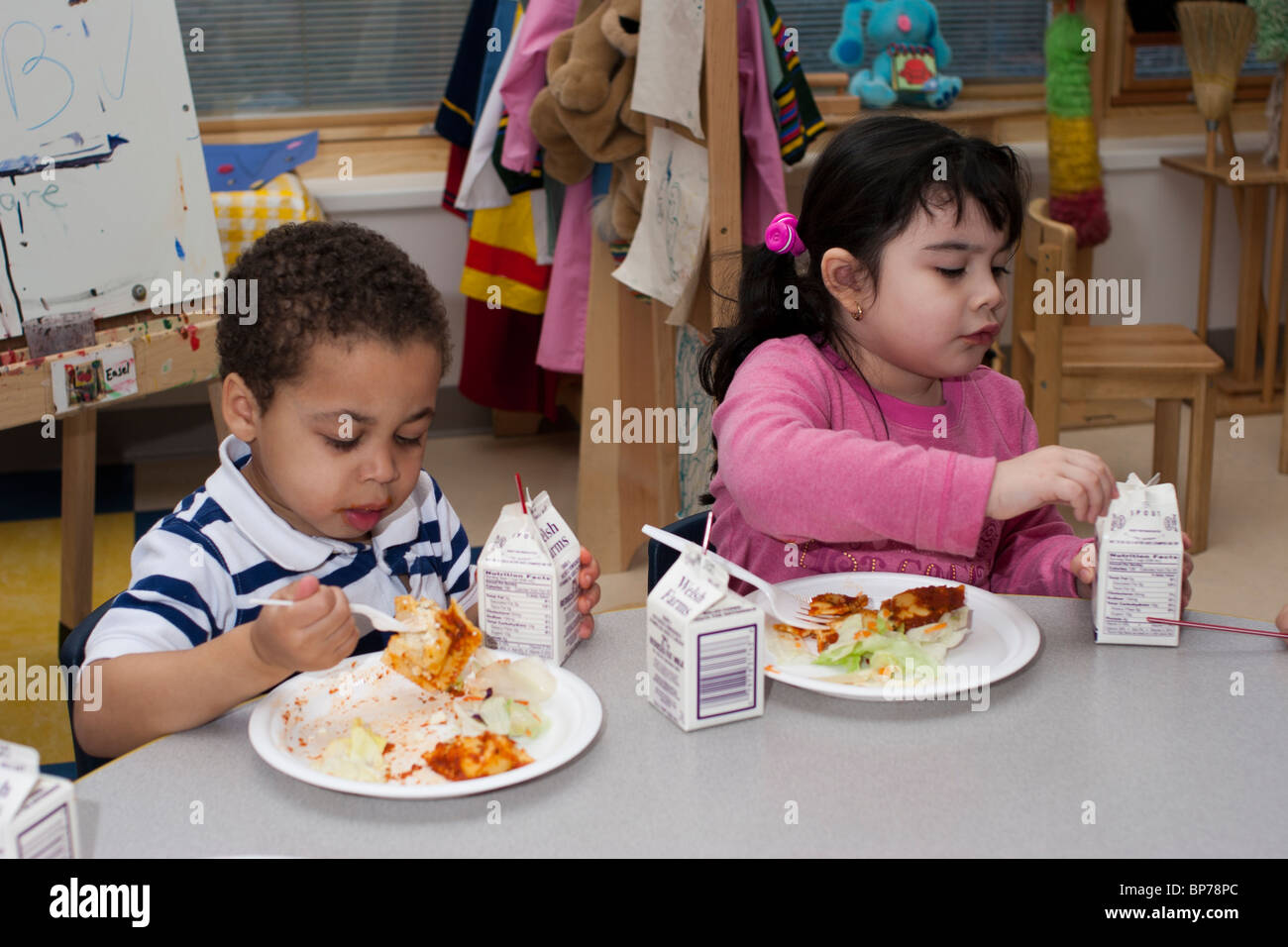 dos niños en edad preescolar de 4 años comer el almuerzo en el aula en