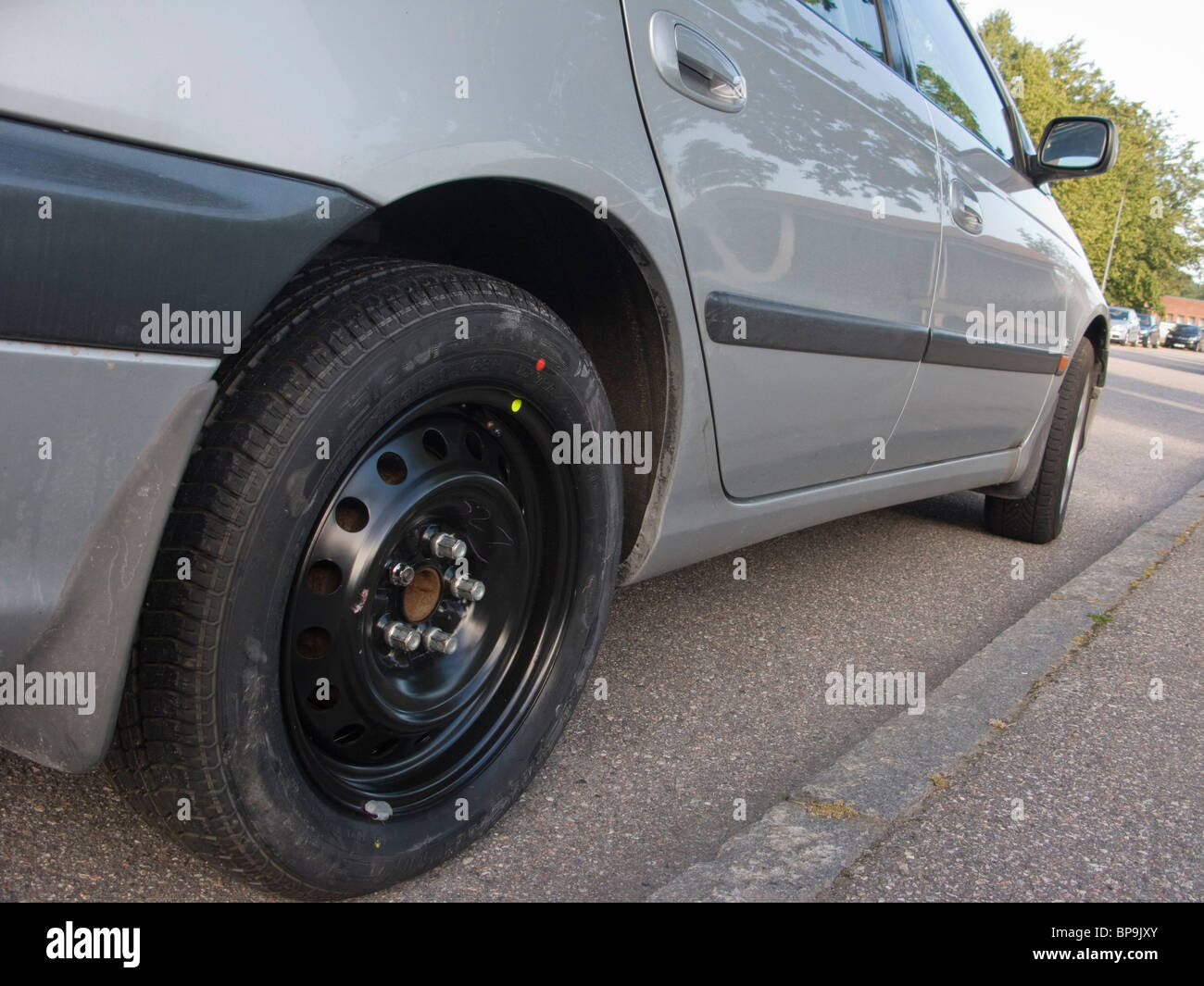 El neumático de repuesto se ha colocado en un coche que ha tenido un pinchazo en la rueda trasera derecha. Foto de stock