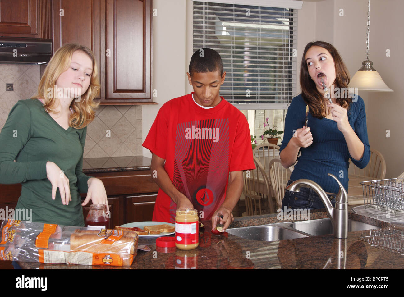 Los adolescentes haciendo el almuerzo, sándwiches de mantequilla de maní y mermelada Foto de stock