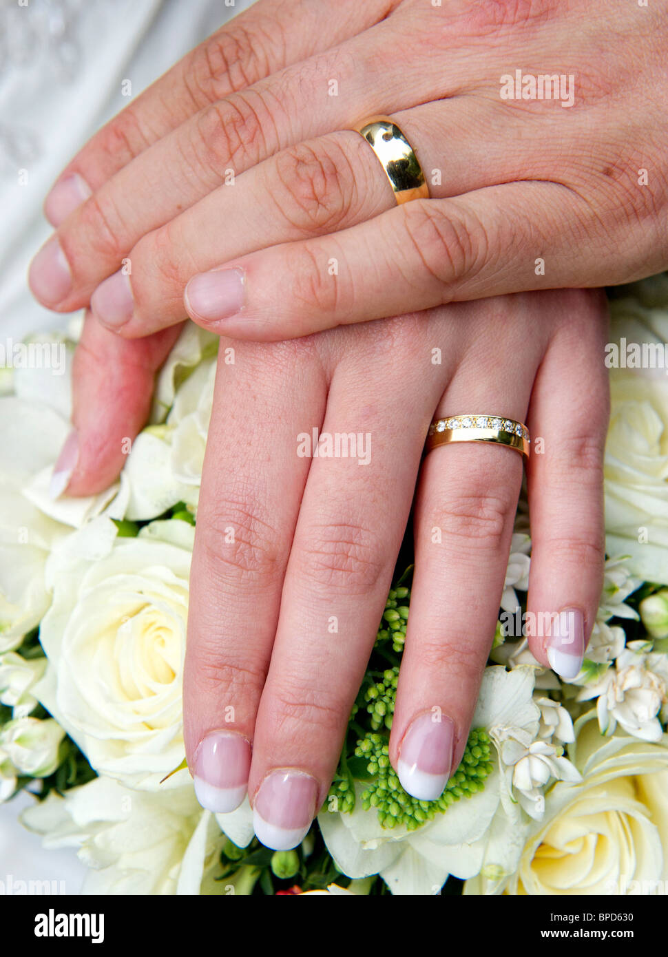 El hombre y la mujer con las manos sobre el ramo de flores y mostrando los  anillos de boda Fotografía de stock - Alamy
