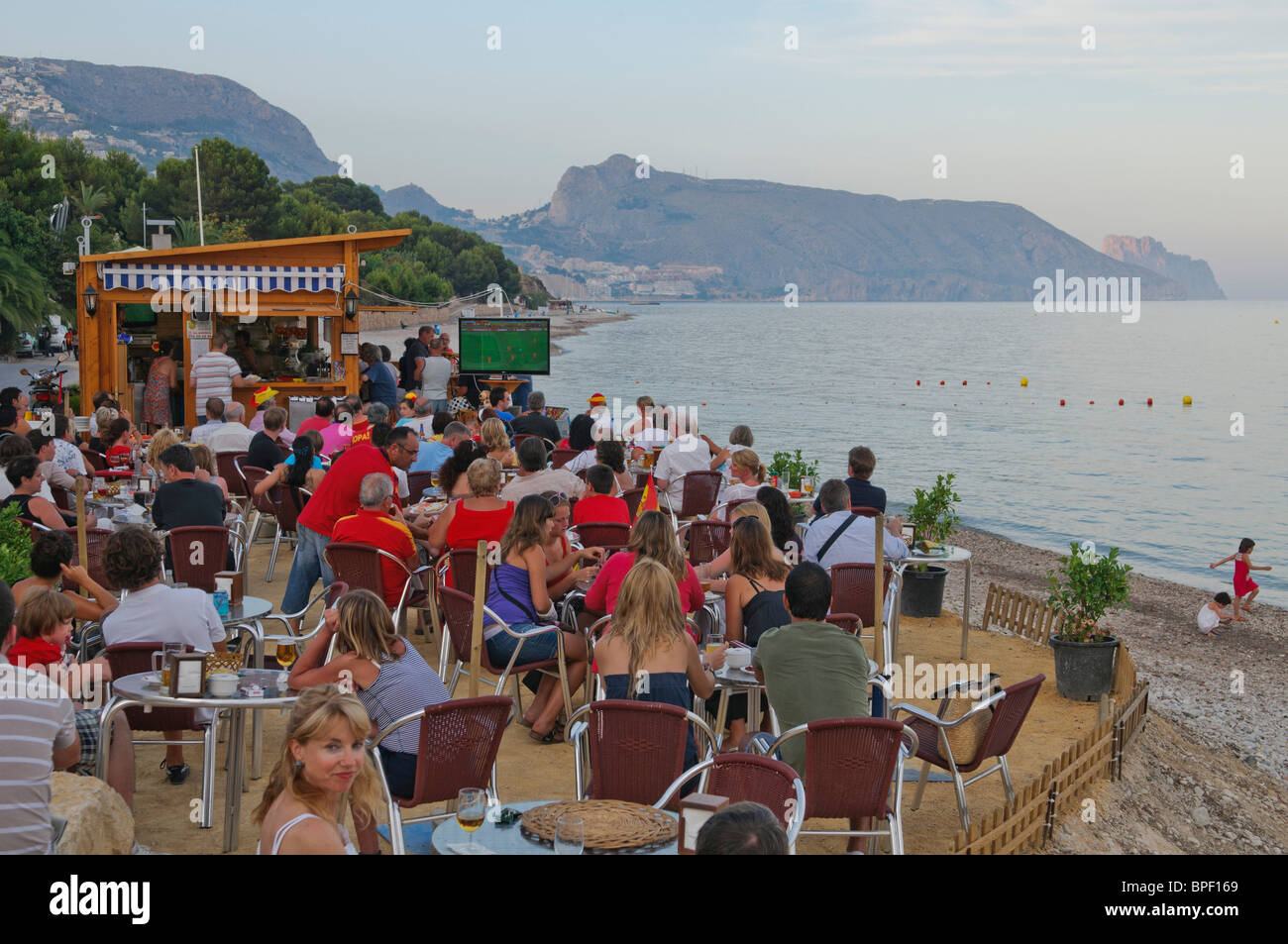 Los aficionados al fútbol ver la Copa Mundial de la FIFA 2010 Final en  grandes pantallas de televisión fuera de bar en la playa, cerca de Altea en  la Costa Blanca, España