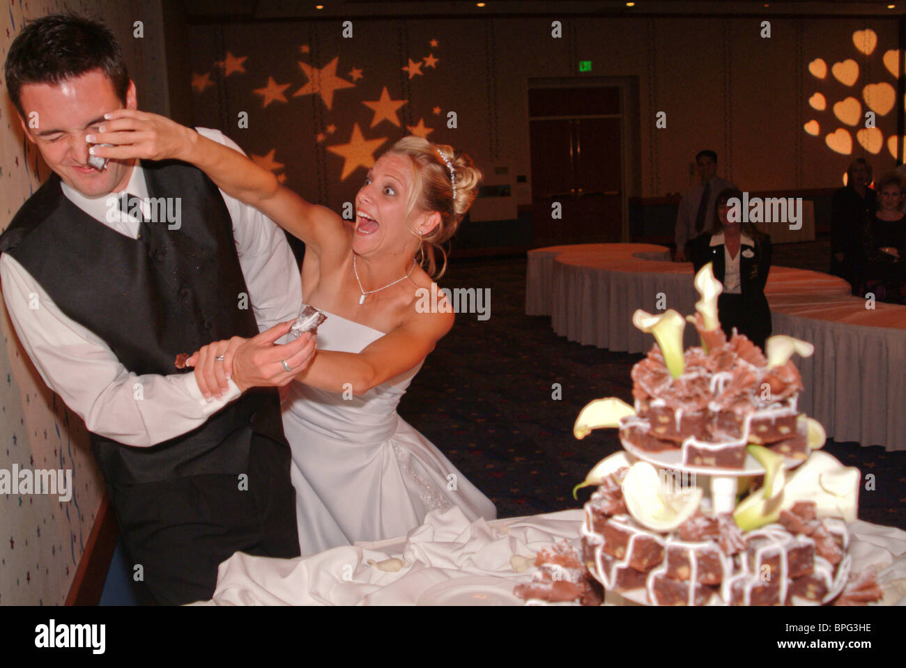 Hermosa recién casados cortando el pastel de bodas novia poniendo la torta en novios cara Foto de stock