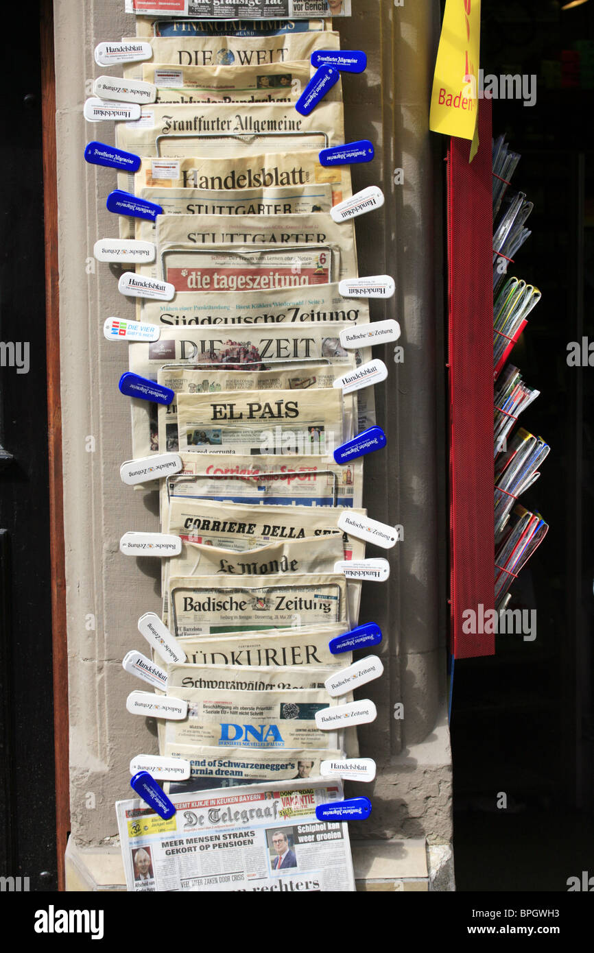 Alemán, Holandés, Italiano y Español periódicos en venta fuera de una tienda de papel en Freiburg im Breisgau, Alemania Foto de stock