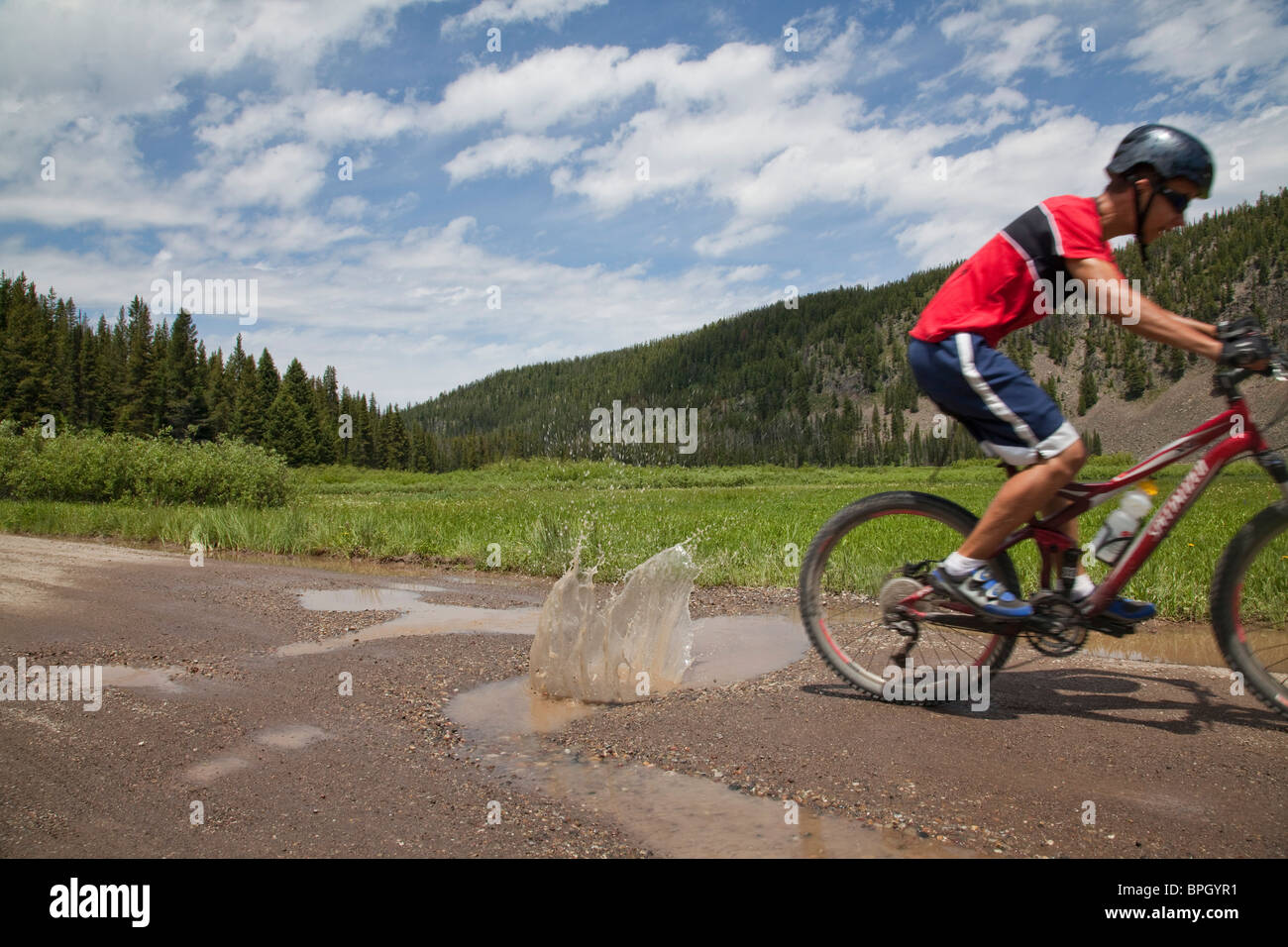 Teen montando bicicleta a través del agua. Foto de stock