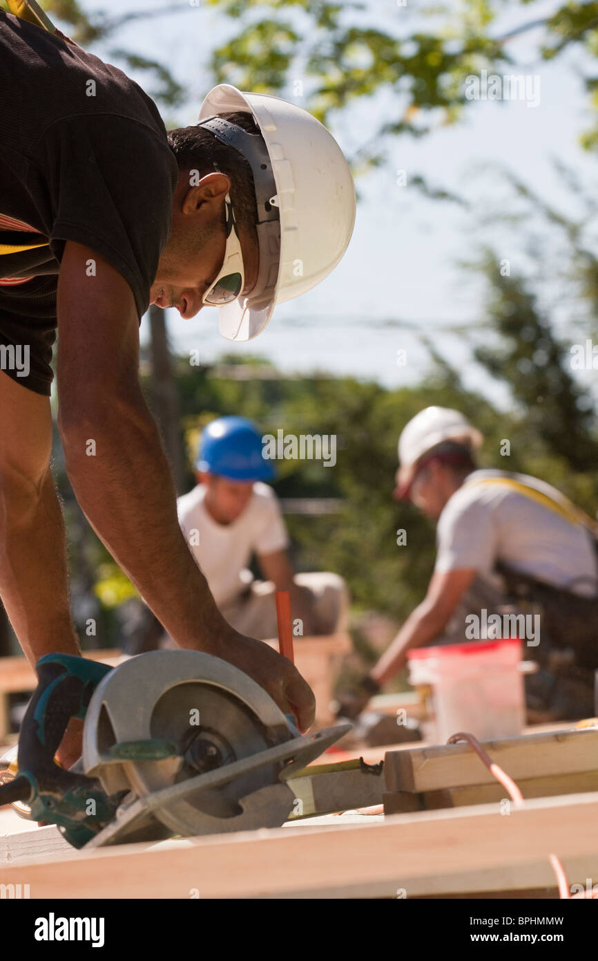 Carpinteros usando una sierra circular en un sitio en construcción Foto de stock