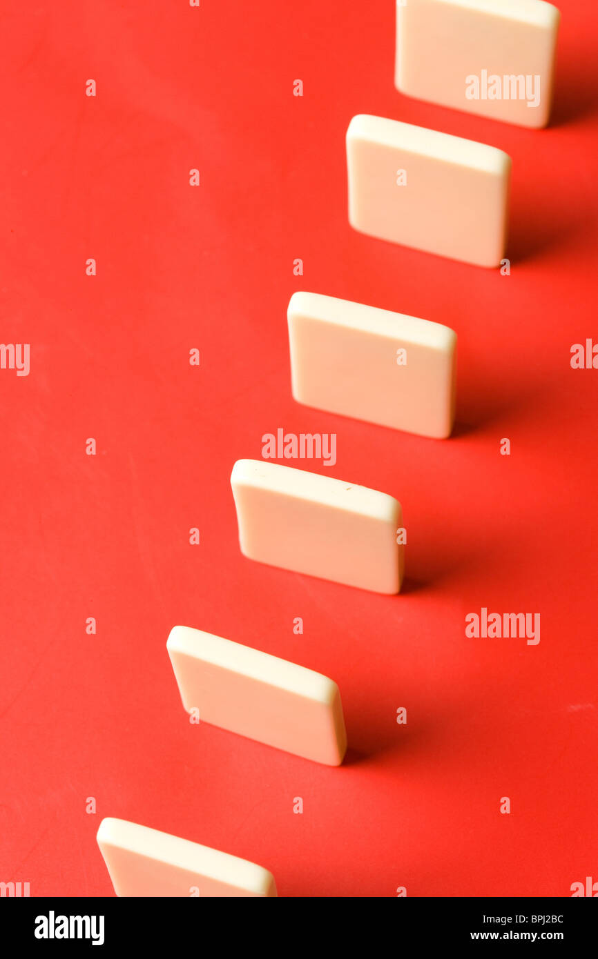 Domino con fondo rojo, el concepto de causa o de trabajo en equipo Foto de stock