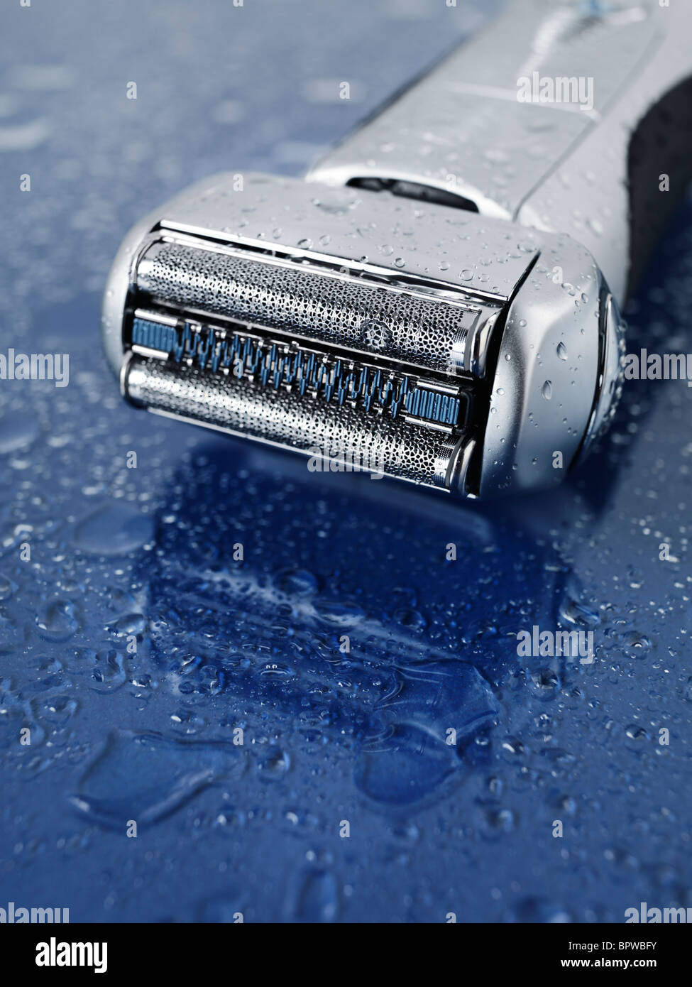 High-end lámina afeitadora eléctrica en wet blue de fondo de vidrio con gotas de agua sobre ella Foto de stock