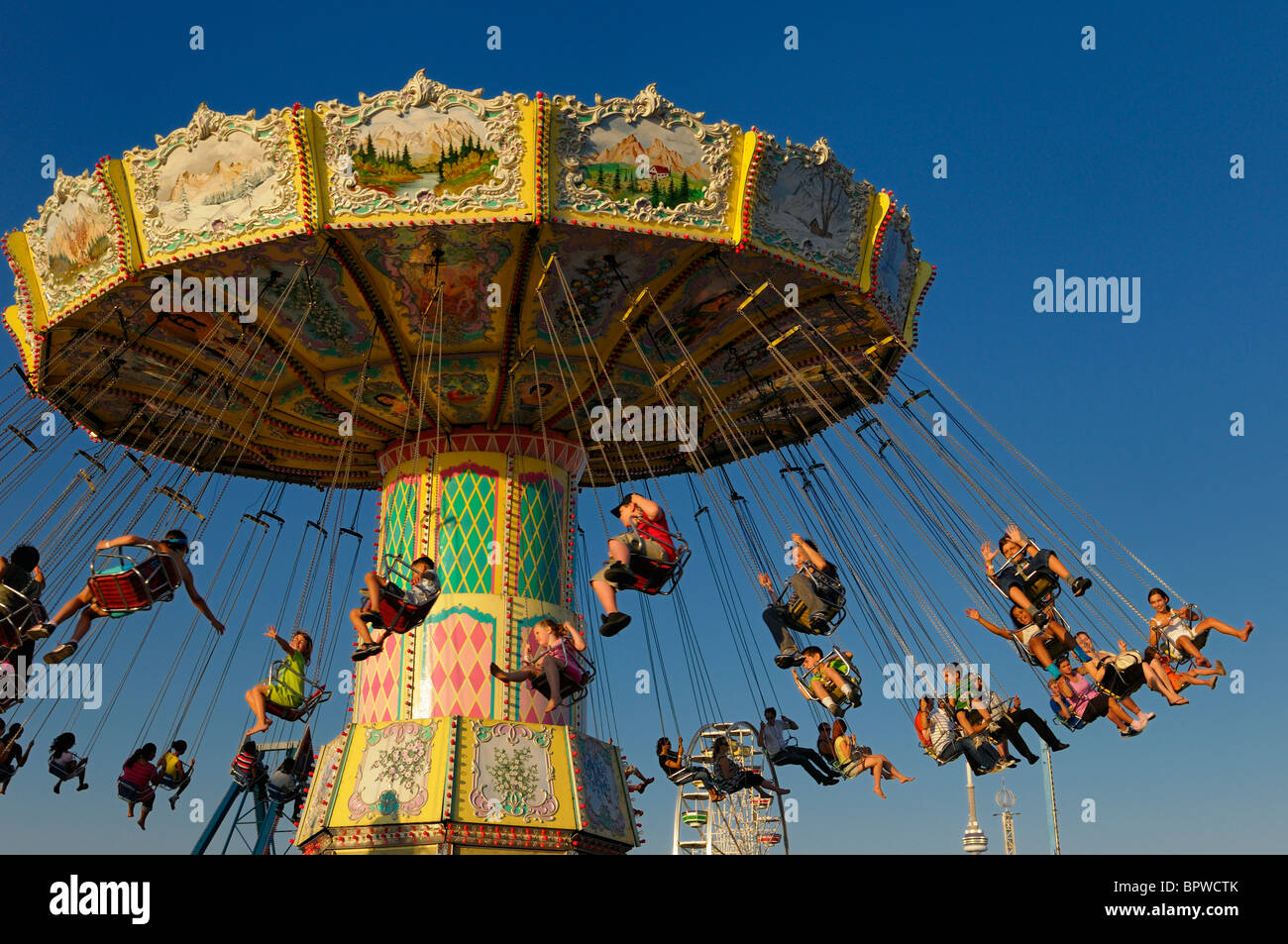 Los niños en la antigua spinning swing ride al atardecer en el Toronto