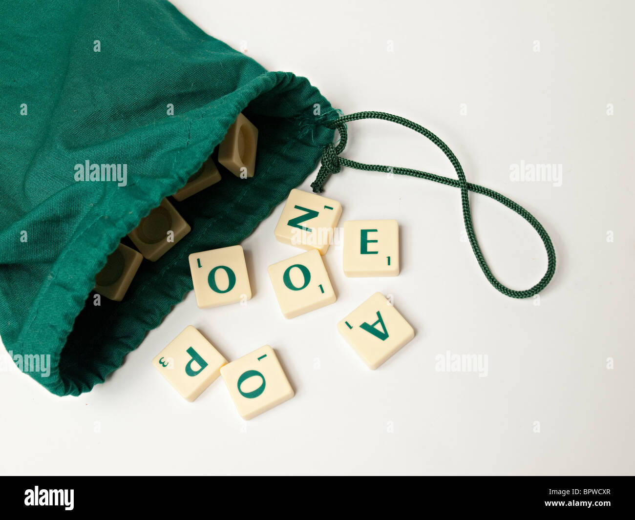 Scrabble azulejos caerse de una bolsa verde Foto de stock
