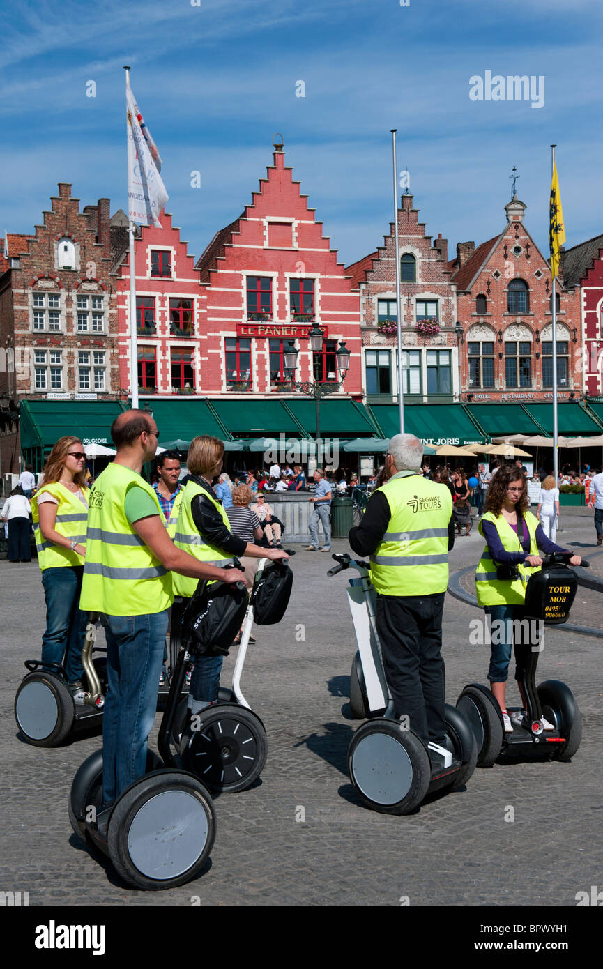 Grupo de turistas en el recorrido histórico de Brujas sobre vehículos eléctricos Segway en Bélgica Foto de stock
