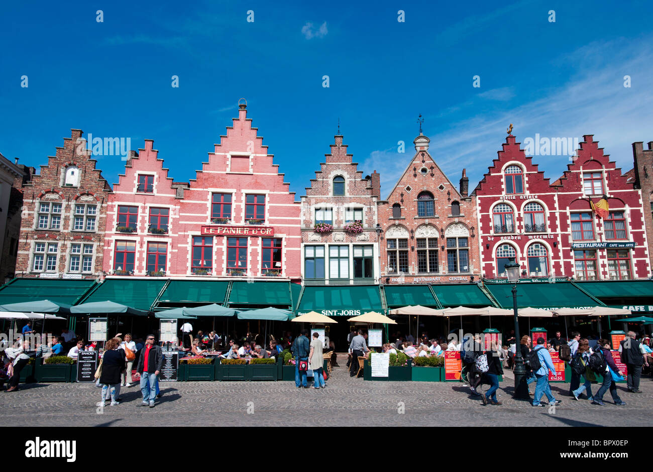 Fila de ornamentados edificios históricos y restaurantes en la plaza del mercado de Brujas en Bélgica Foto de stock