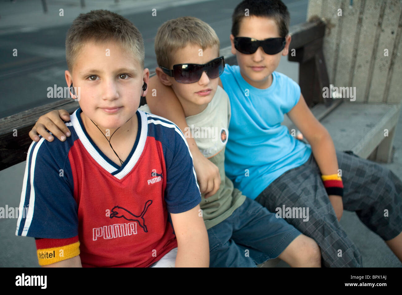 Muchachos, dos con gafas de sol y uno con un personal stereo, sentarse en un banco en la calle, Sarajevo, Bosnia Foto de stock