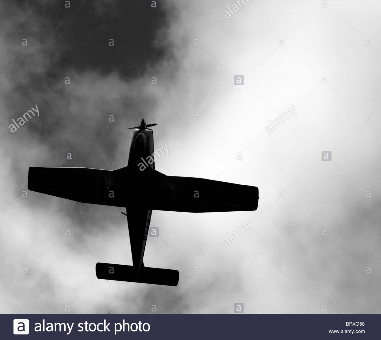 Avión de hélice silueteado contra el cielo nublado Foto de stock