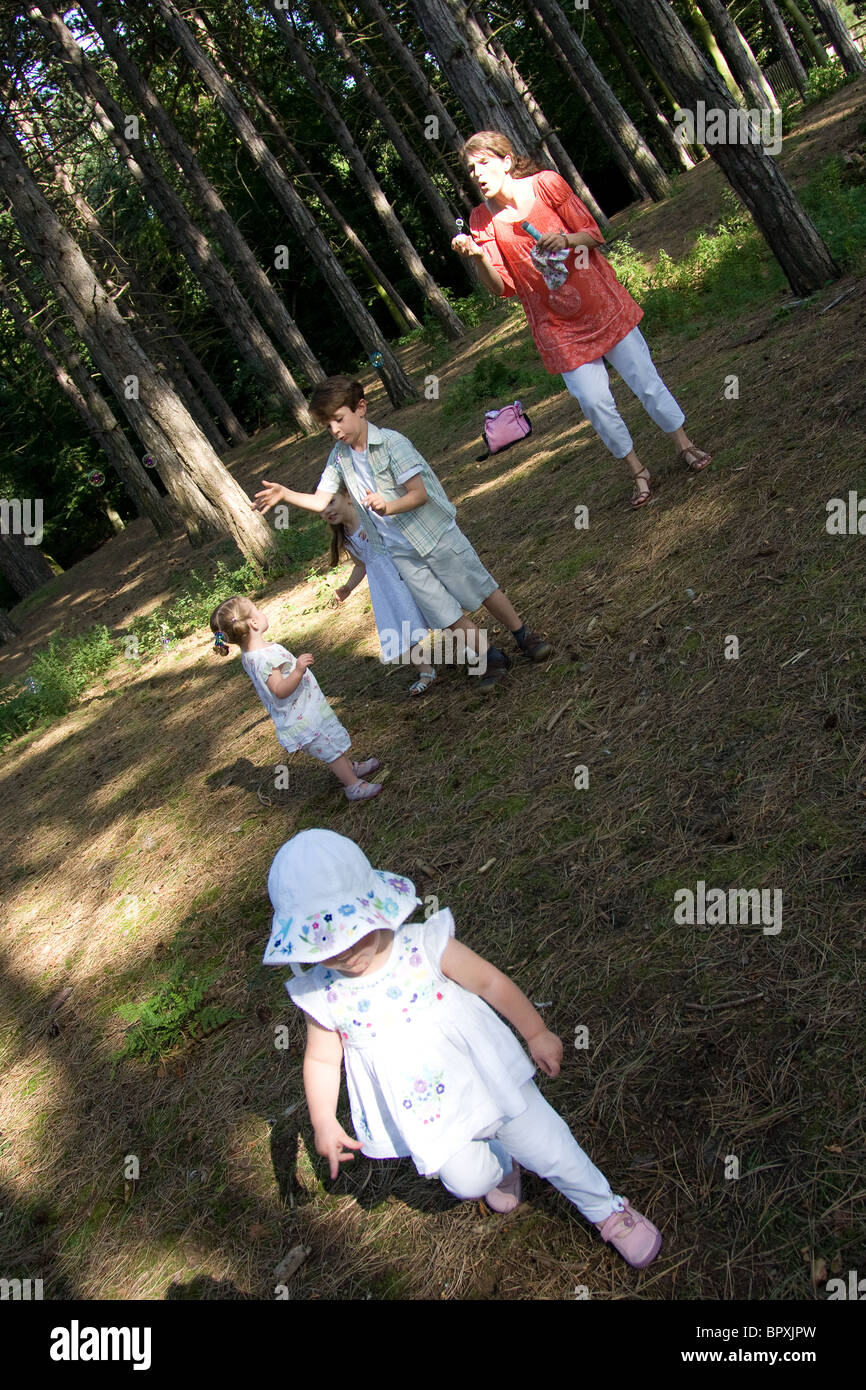 Familia niños jugando en el bosque hermanas jóvenes Foto de stock