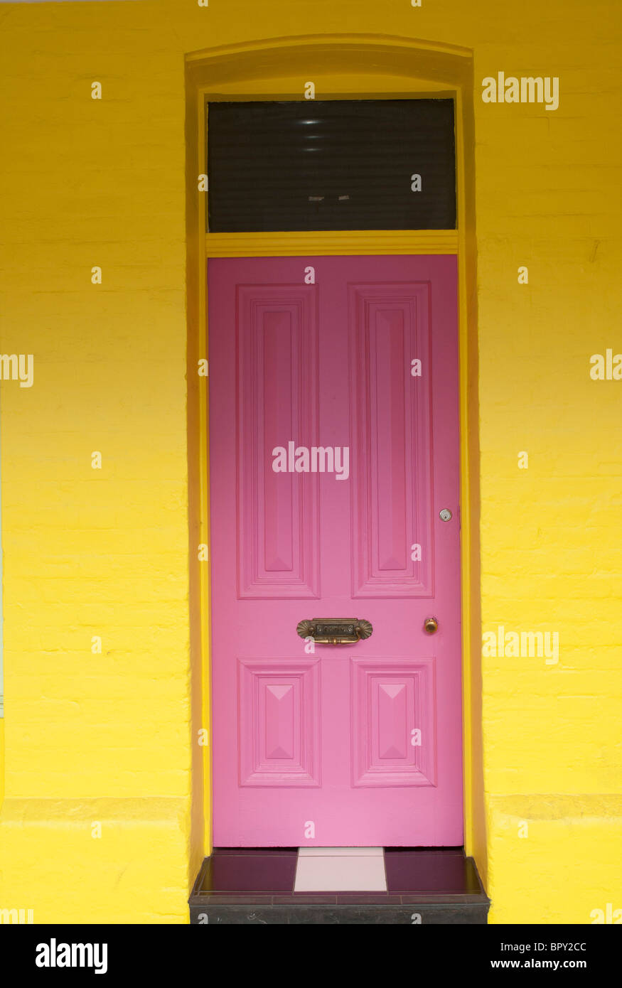 Rosa Brillante puerta contra una pared de color amarillo vivo Foto de stock