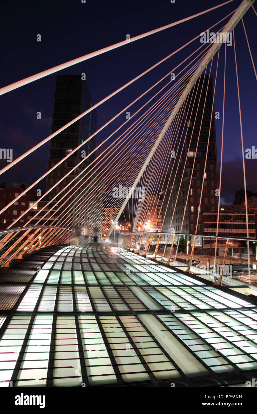 Imagen nocturna del Puente Zubizuri cruzando el río Nervión en Bilbao, España. Foto de stock