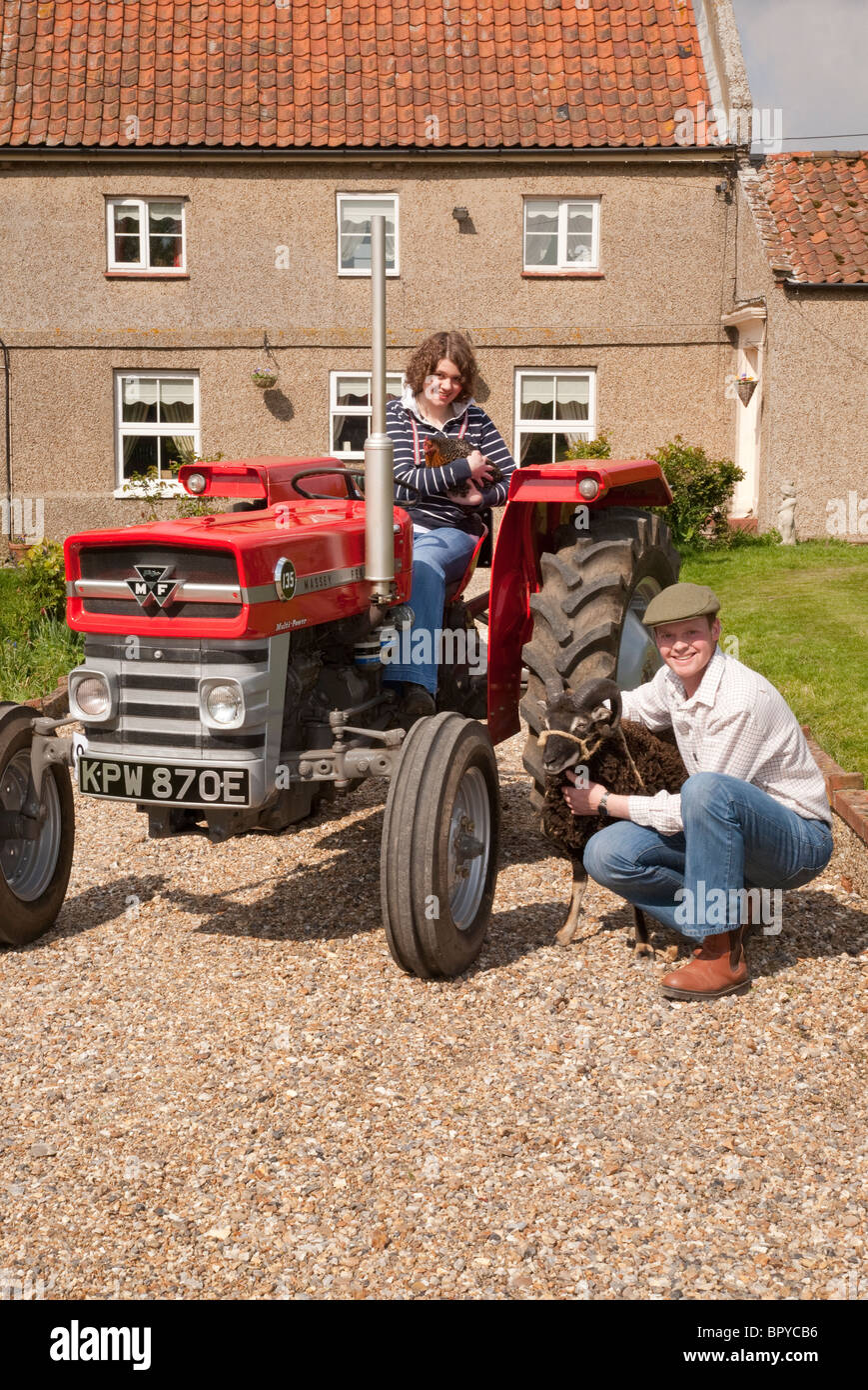 Una joven pareja sonriendo ante la Cámara agrícola fuera una granja con un  tractor vintage, gallina y RAM Fotografía de stock - Alamy