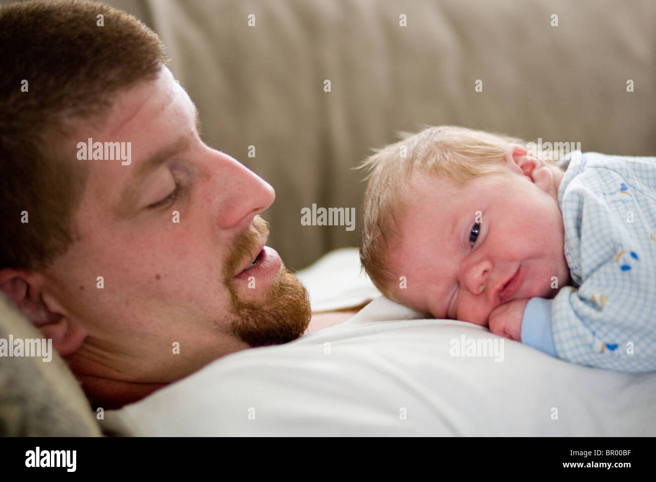 Un bebé y su padre pegado. Foto de stock