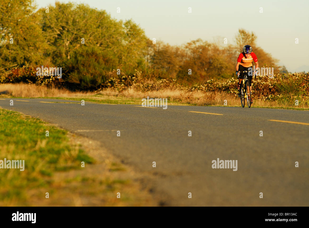 Una mujer es el ciclismo de carretera a Playa atsunset Iona, Richmond, British Columbia, Canadá. Foto de stock