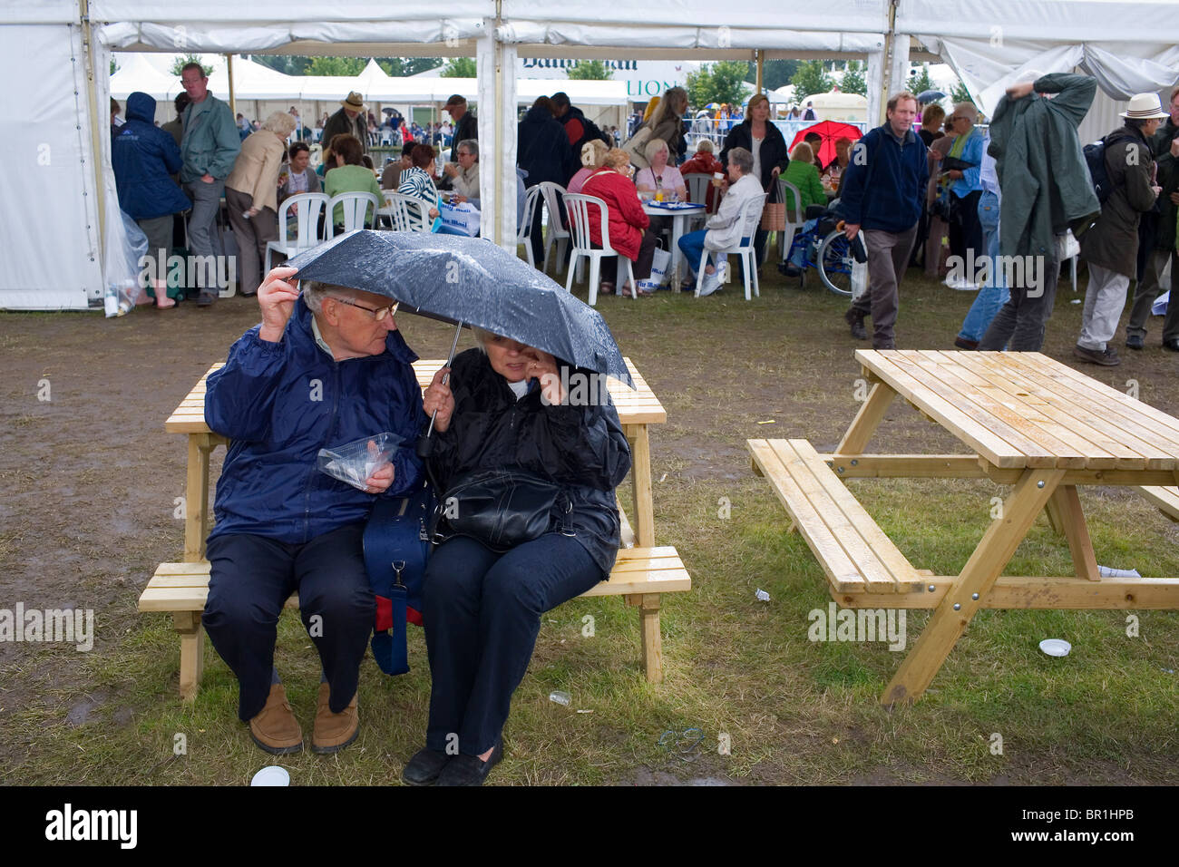 Dos personas se apiñan bajo una sombrilla en la Hampton Court Flower Show. Foto de stock