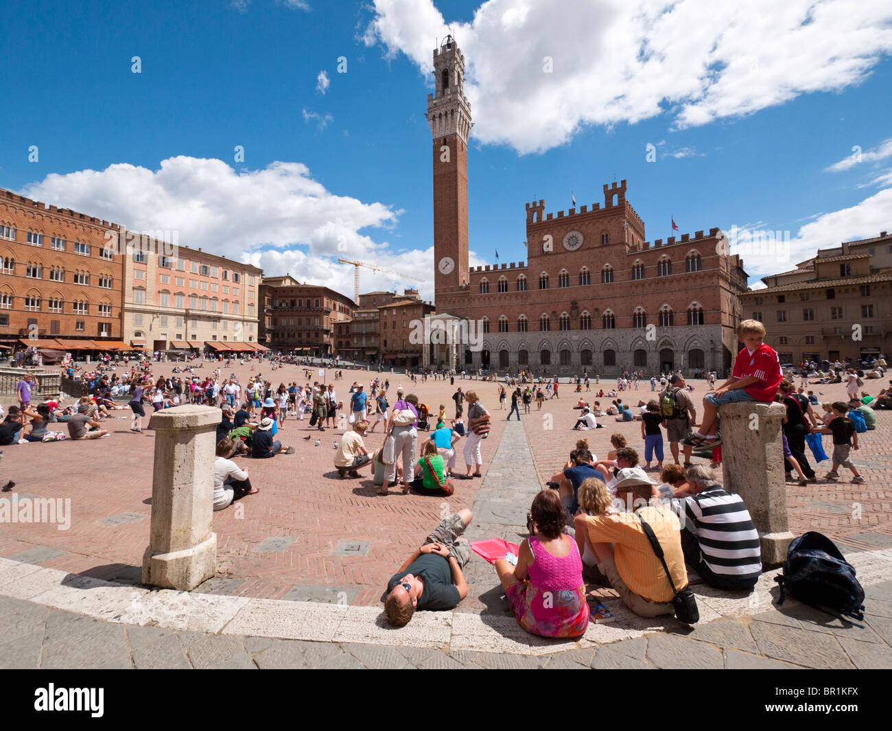 Los turistas visitan 'Il Campo', la plaza central en el casco antiguo de la ciudad de Siena, en la Toscana, Italia. Foto de stock