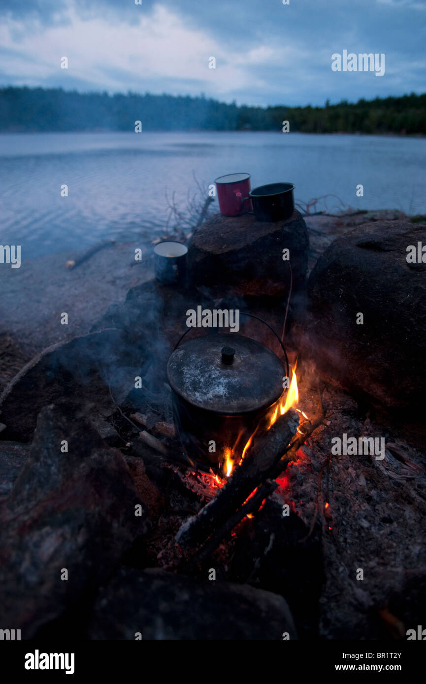 Juego de copas de Esmalte sobre las rocas alrededor de una fogata esperar la olla hervir en Johnny, Killarney Provincial Park Lake, Ontario Foto de stock