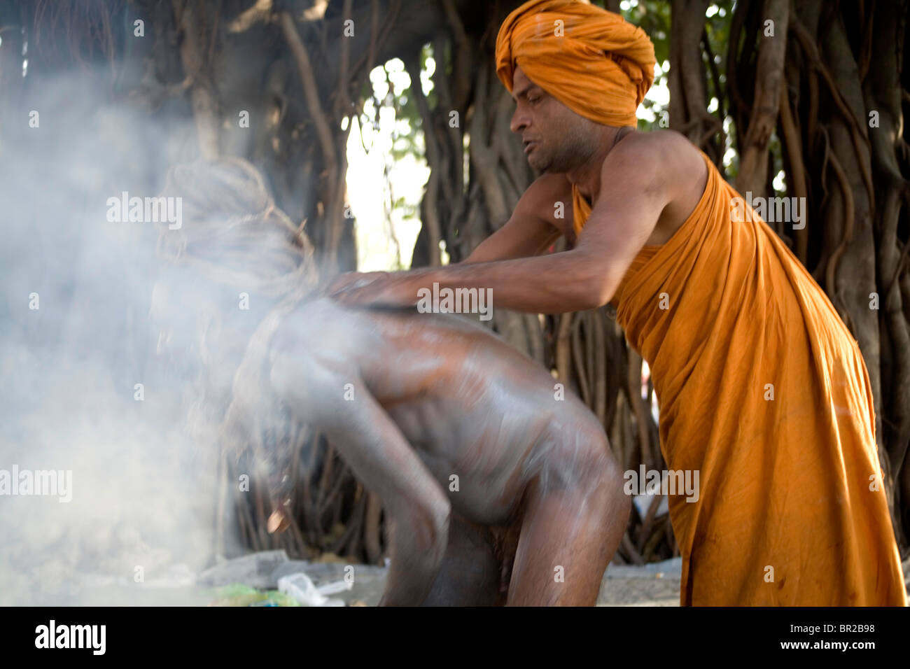 Un hombre santo Sadhu es ayudado por su asistente para poner cenizas en su cuerpo para el festival Kumbh Mela Haridwar, Uttarakhand, India. Foto de stock