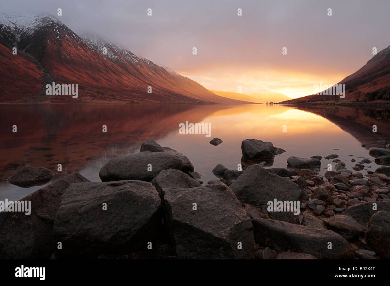 Luz llameante de una puesta de sol de invierno ilumina Loch Etive en las Tierras Altas de Escocia. Foto de stock