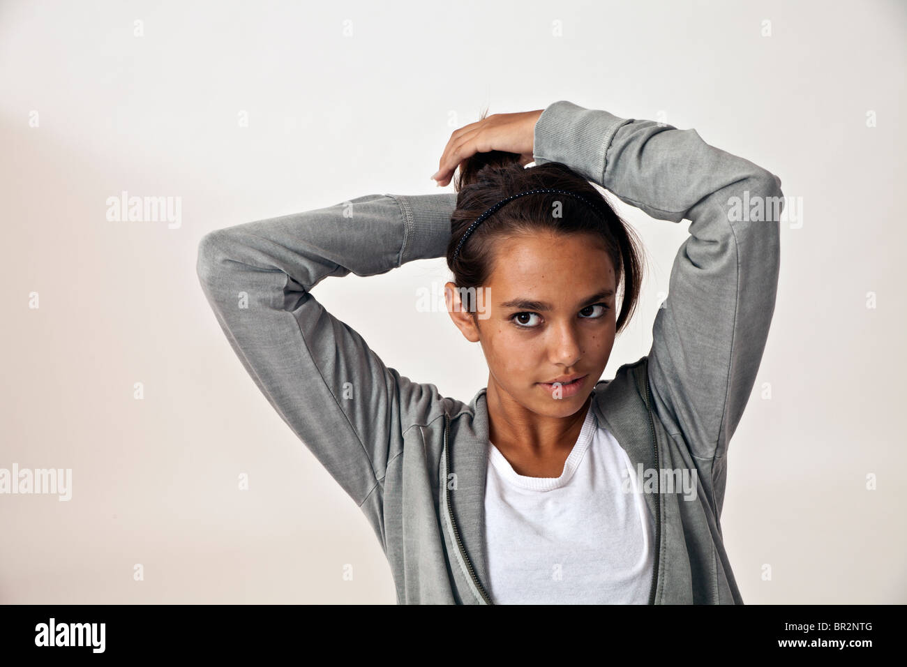 Étnicamente diversa jovencita 14-16 años vistiendo un suéter gris chica hispana halarse el cabello en cola de caballo. persona personas señor © Myrleen Pearson Foto de stock