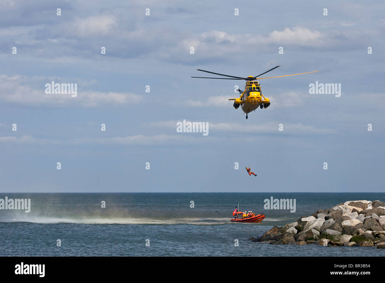 RAF Mar Rey, baja un helicóptero de rescate winchman sobre a esperar un salvavidas RNLI de bajura. Foto de stock