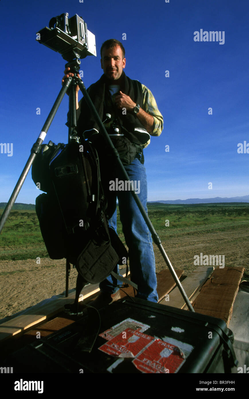 Un fotógrafo está encima de un jeep, usando una cámara de gran formato, en un de caza y lodge cinco estrellas en Kenya Fotografía de stock -