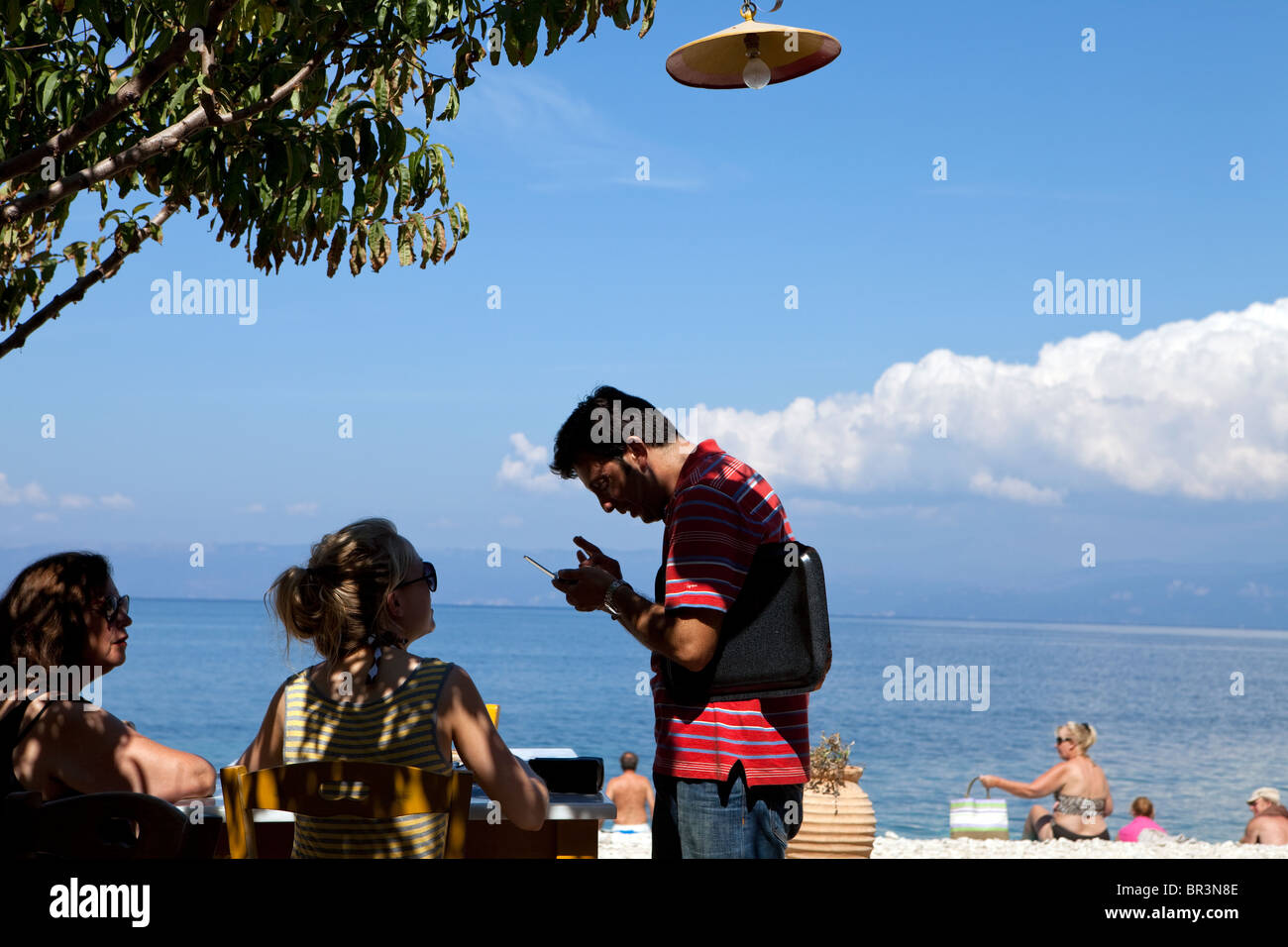 Camarero teniendo comida fin en Taverna cerca playa Levrehio, Paxos. Foto de stock