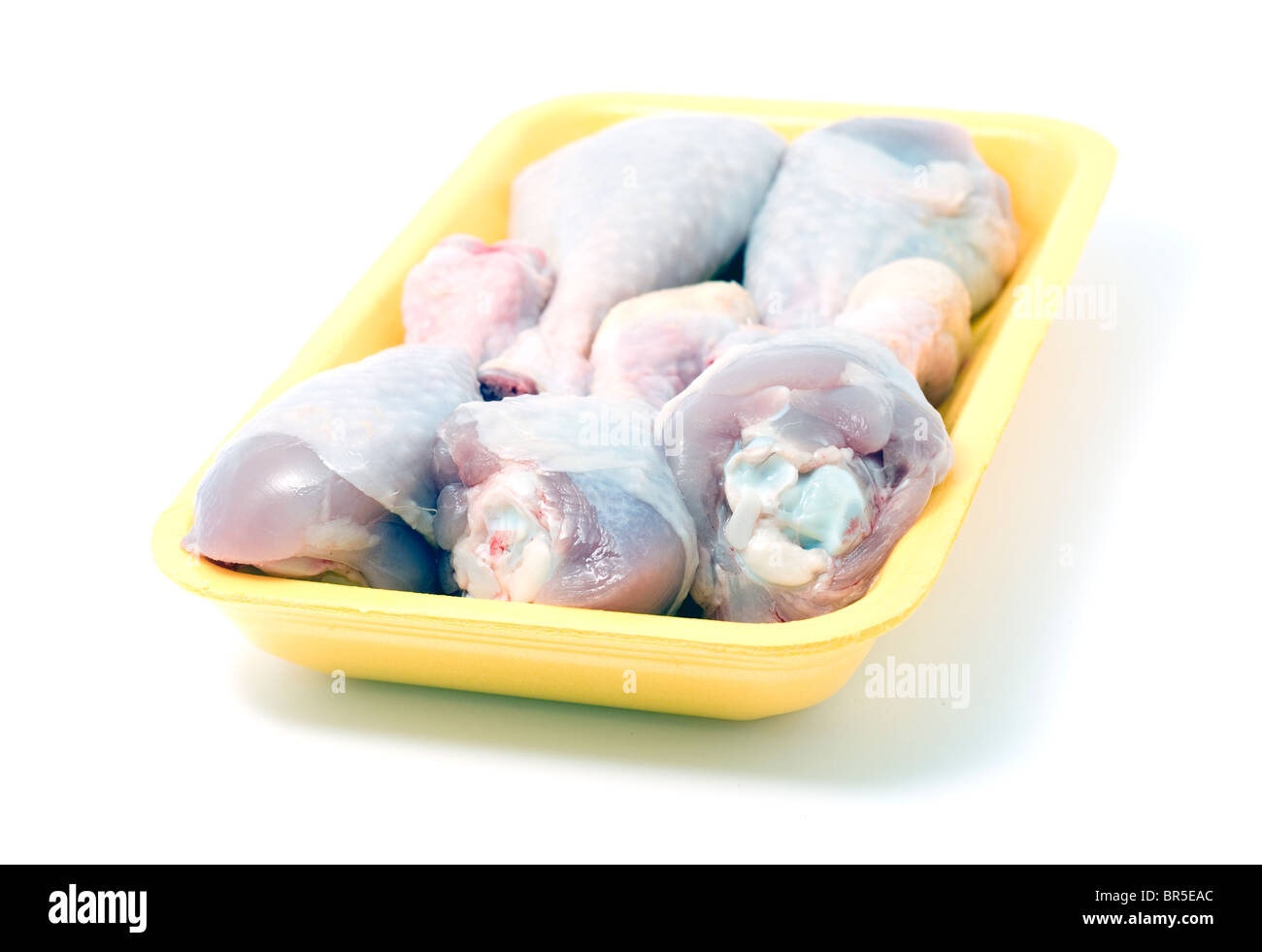 Piernas de pollo crudo en el envasado al vacío. Aislado en blanco. Foto de stock