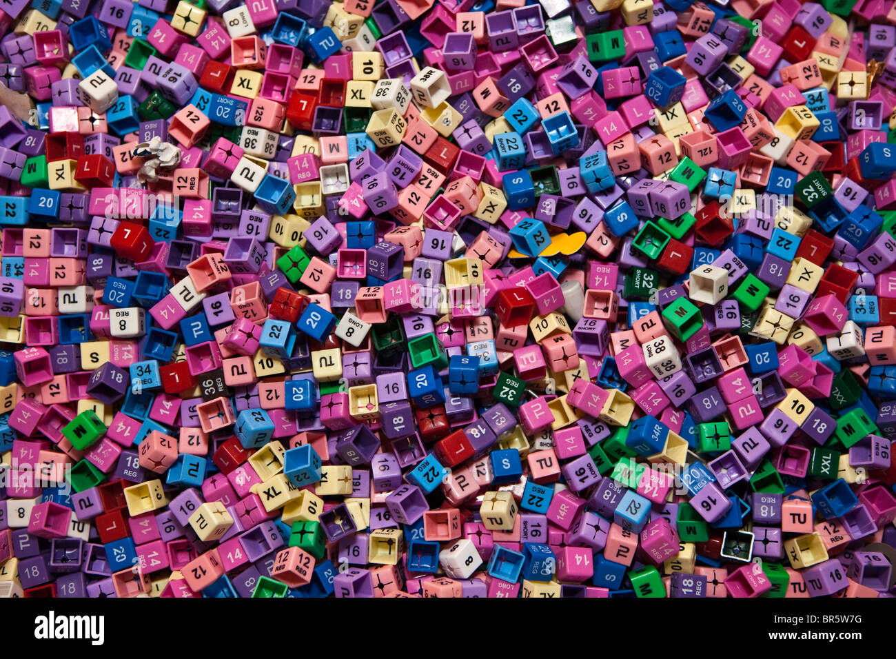Cientos de etiquetas de ropa de plástico, mostrando todos los tamaños y colores diferentes programaciones. Foto de stock