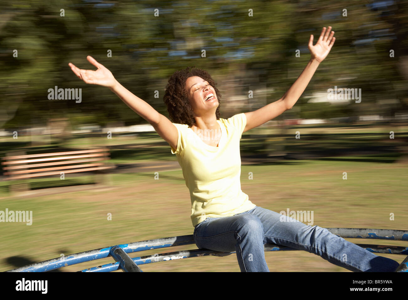 Mujer joven montando en la rotonda en el parque Foto de stock