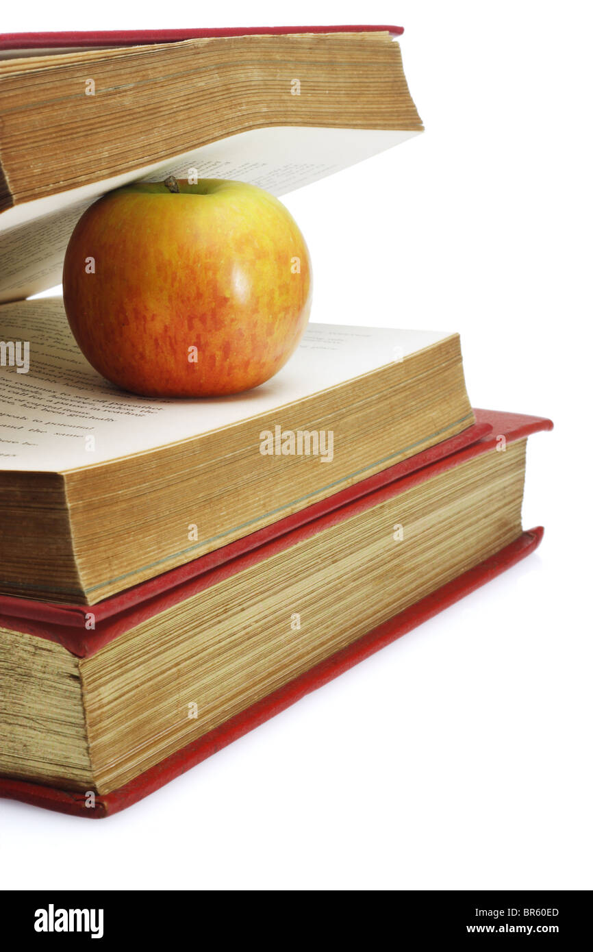 Manzana roja entre las páginas del viejo libro sobre fondo blanco. Foto de stock