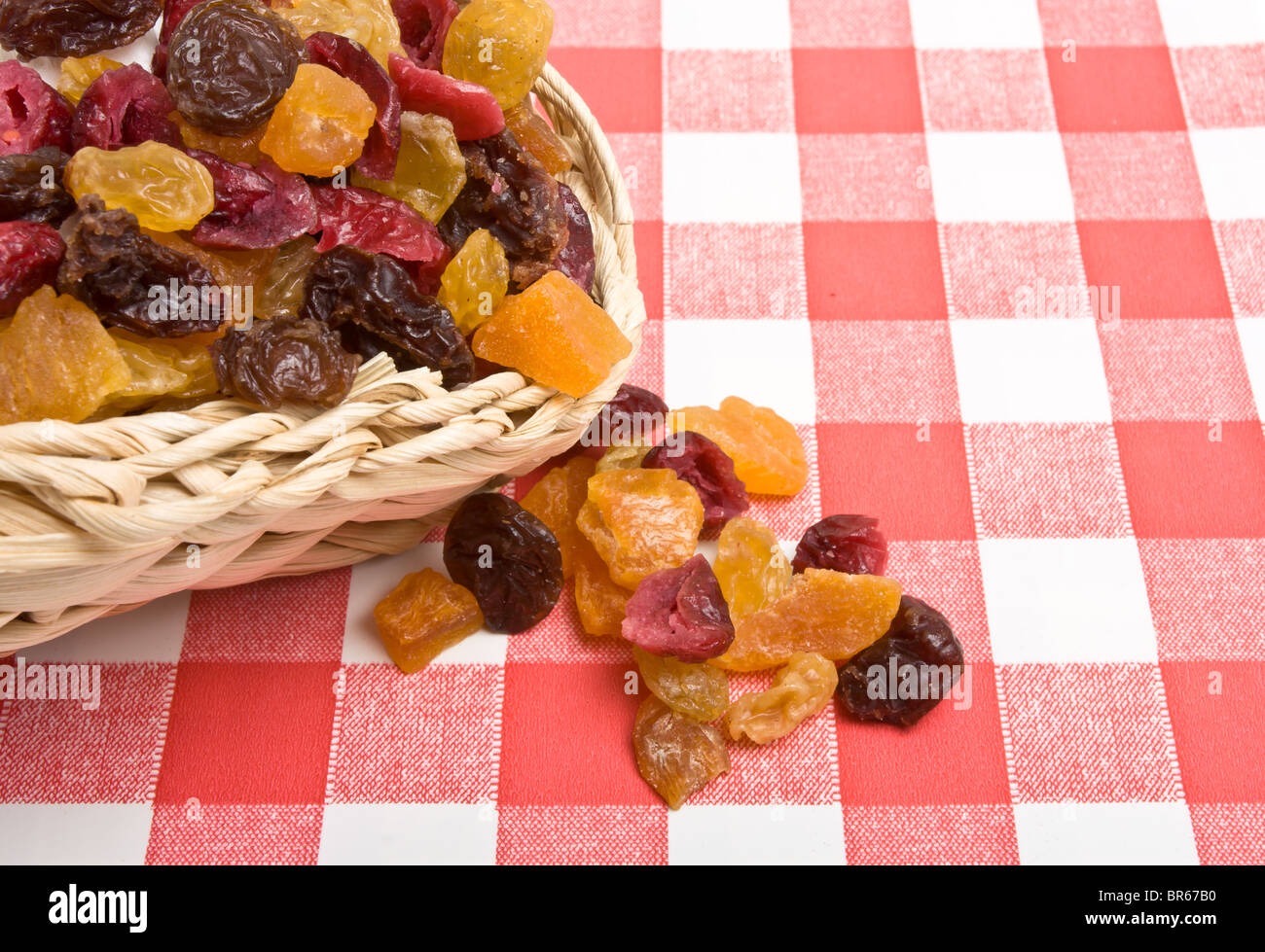 Frutos secos de albaricoque, Sultana, pasas y arándanos derramándose sobre el mantel rojo y blanco. Foto de stock