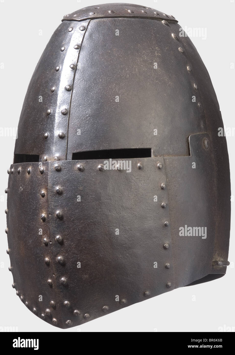 Un gran timón, Período de Historia en el estilo de la primera mitad del siglo 14. Casco hecho de varias piezas de placas de hierro remachadas. Pieza ovalada de corona con cuatro orificios dobles para fijar la cresta. Cráneo de cuatro piezas con una abertura de doble ojo. Visera móvil con un pestillo en el lateral. Una grapa en ambos lados para las correas. Altura 32 cm. Histórico, histórico, siglo 19, armas defensivas, armas, armas, arma, brazo, dispositivo de lucha, objeto, objetos, alambiques, recortes, recortes, recortes, recortes, utensilio, pieza de equipo, utensilios, chapado, blindaje-chapado, Foto de stock