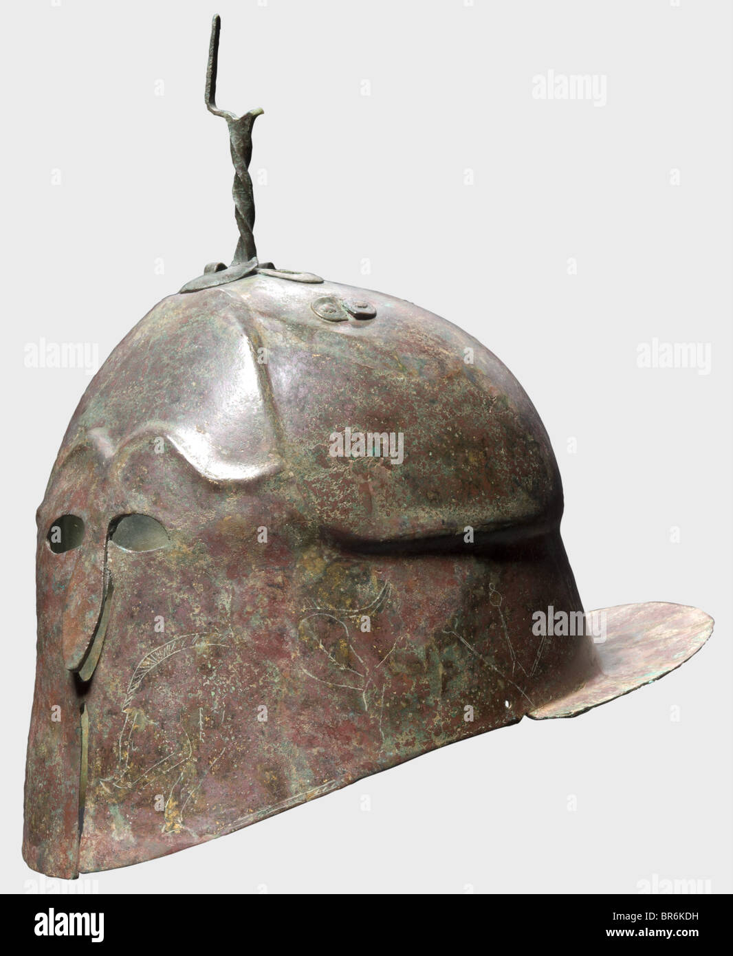 Un casco Apuliano-Corinthiano, Bronce del siglo V a.C. Casco alto con habilidad claramente desplazada, hastial y cejas contorneadas. Cortes de ojos pequeños y un nasal robusto y sobresaliente. Los guardas de mejillas se abren en frente, conectados por un puente y llevan representaciones antitéticas de jabalíes y motivos de plantas de tres tallos. La parte trasera del cuello está decorada con caballos. El cráneo montado por un tenedor de cresta retorcido soldado y remachado, junto a él restos de otro soporte. Orificios para la correa en ambos lados. Protector de cuello ancho y horizontal, perforado dos veces. Altura total 2, Foto de stock