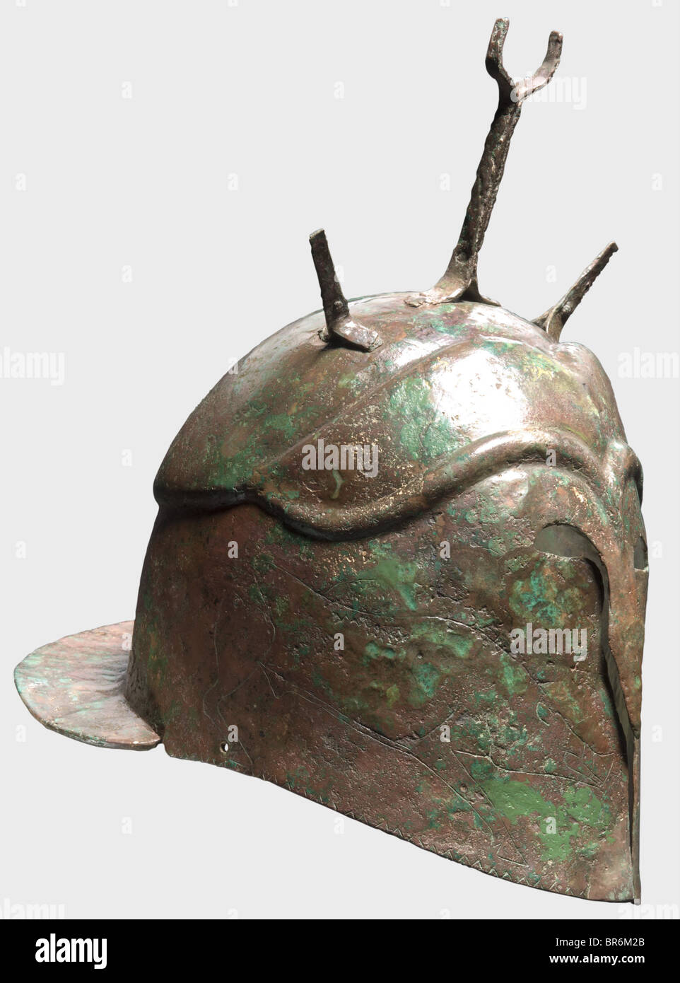 Un casco Apuliano-Corinthiano, Bronce del siglo V a.C. Claramente desplazamiento del cráneo, protectores cerrados de mejillas con puentes, pequeños cortes oculares, protuberancias nasales y cejas fuertemente moldeadas y sección de frente. Grandes representaciones de jabalíes a cada lado. El perímetro decorado con un patrón triangular. En la corona, una horquilla remachada en la cresta flanqueada por lengüetas más cortas, agujeros en el aro del casco para el accesorio de la correa. Muescas cortas delante del protector ancho del cuello. Altura 17.3 cm, con horquilla de cresta 27.3 cm, peso 710 g. Pátina rojo-marrón a verde, corrosión severa en lugares, , Foto de stock