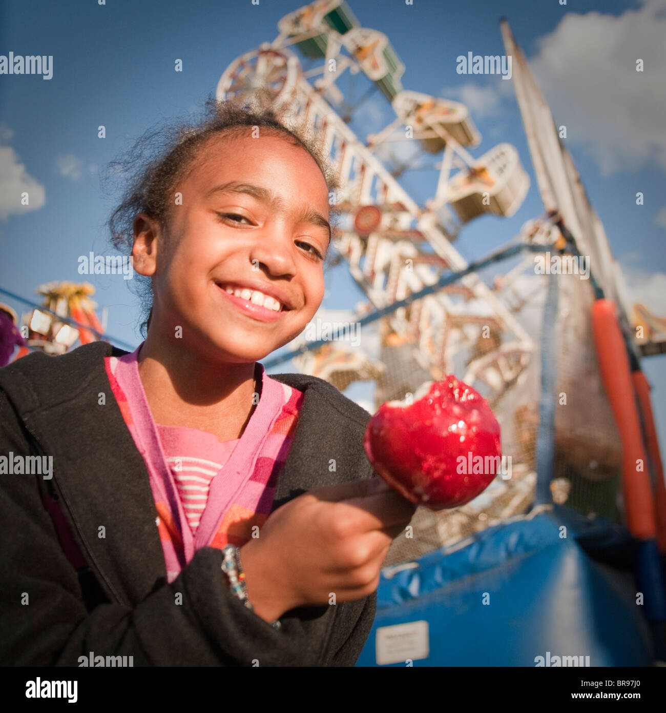 Chica Que Come Una manzana confitada en una feria del condado/estado Foto de stock