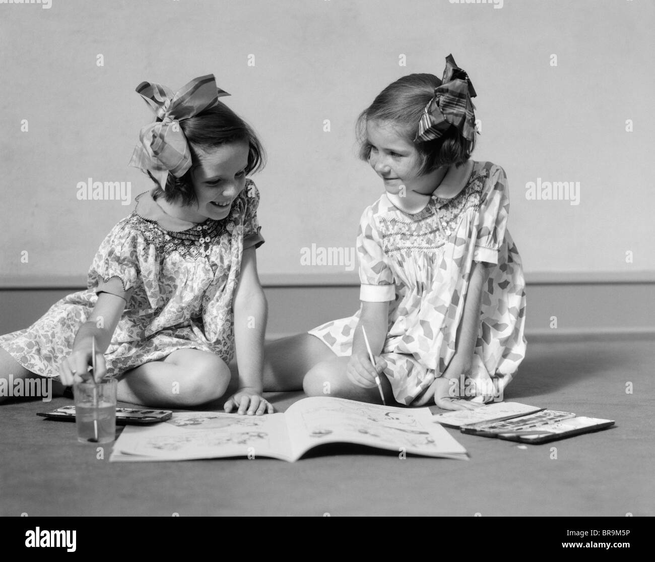 1930 dos niñas PINTURA EN LIBRO CON acuarelas Foto de stock