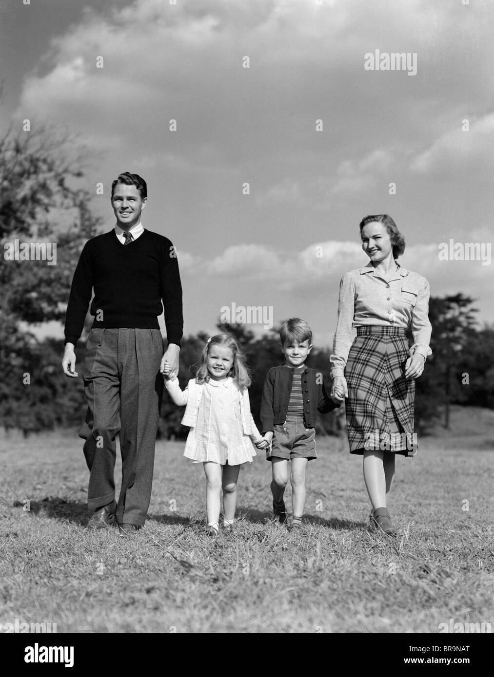 1940 Familia tomados de la mano caminando sobre hierba Foto de stock