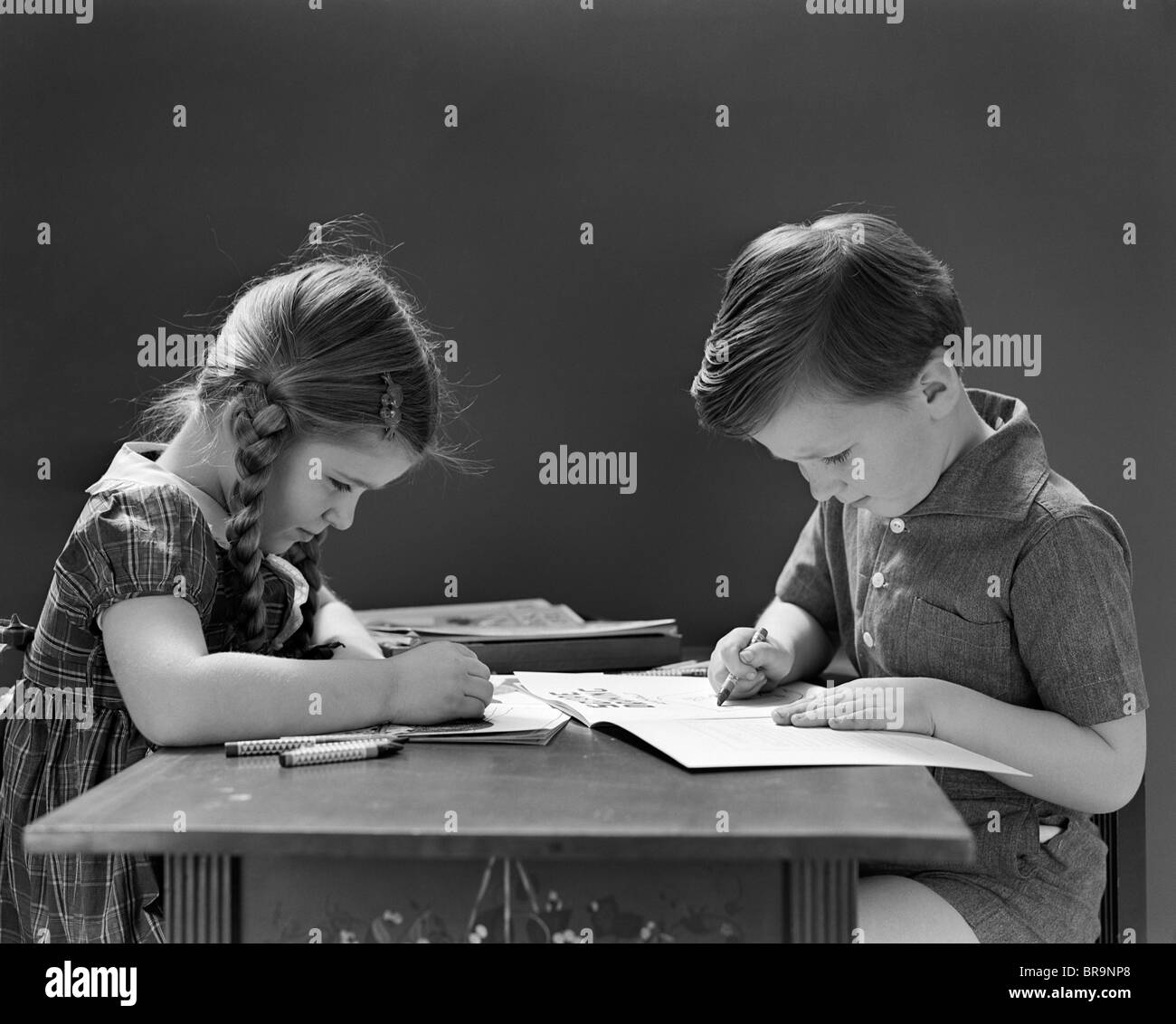 1940 chico y chica colorear LIBRO SENTADO EN LA MESA Foto de stock