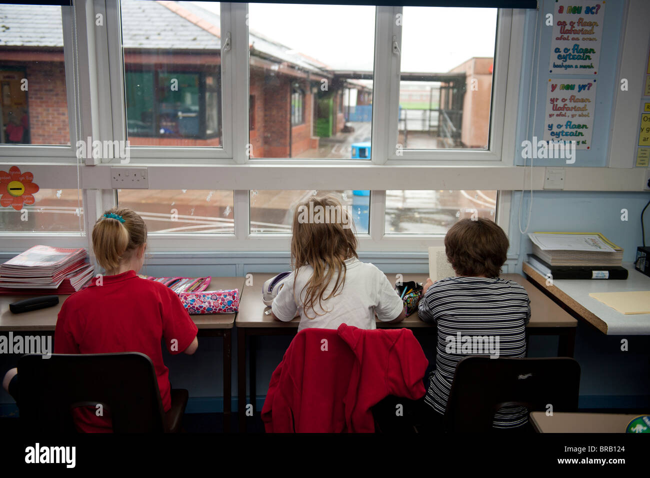 Vista trasera de tres niños de la escuela primaria está sentado en su escritorio, REINO UNIDO Foto de stock